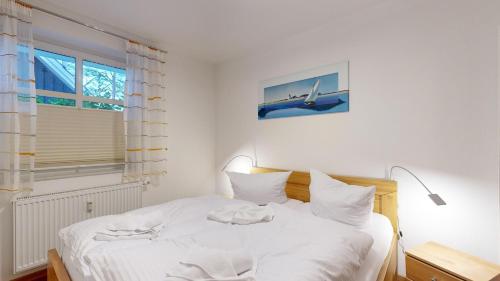 a bedroom with a white bed with a plane picture on the wall at Caspar David in Binz
