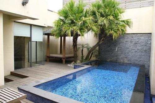 a swimming pool in front of a house with palm trees at Madrid Classic Hotel in Hsinchu City