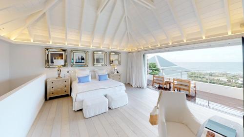 a bedroom with a bed and a balcony with the ocean at Hotel Le Toiny in Gustavia