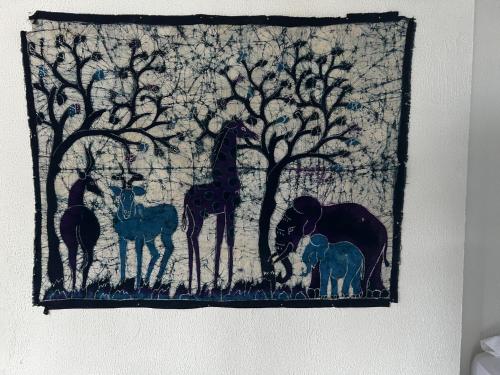 a tapestry with giraffes and other animals on a wall at Hotel Miss Francias Home in Providencia