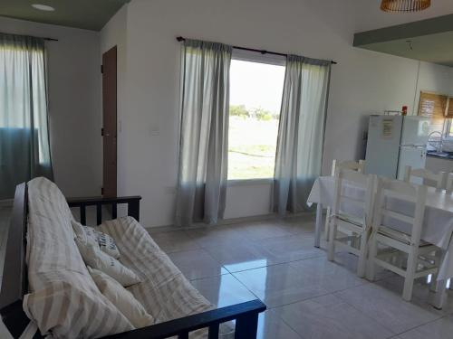ein Wohnzimmer mit einem Tisch, Stühlen und einem Fenster in der Unterkunft Casa Nuevo Sol in Cañada La Negra