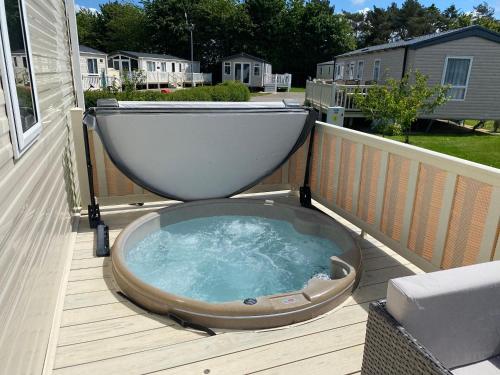 a bath tub sitting on a deck with a toilet on it at Tattershall Lakes Kingfisher Caravan 8 berth with Hot tub & WiFi in Tattershall