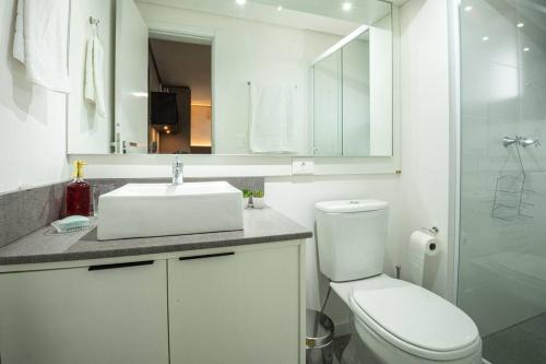 a white bathroom with a sink and a toilet at Loft 804 com vista Parque Una in Pelotas