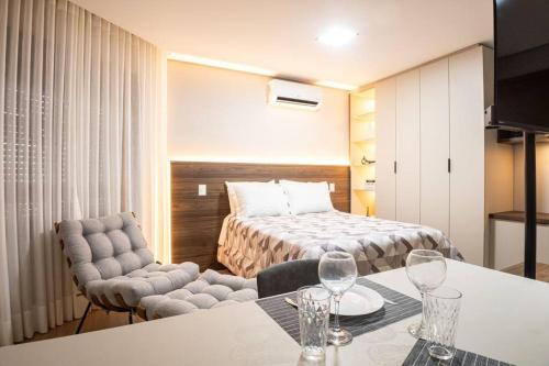 Habitación de hotel con cama, mesa y sillas en Loft 804 com vista Parque Una en Pelotas