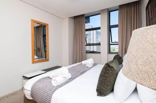a bedroom with a large white bed and windows at Chic 1-Bedroom Apartment In The Heart Of The City in Cape Town