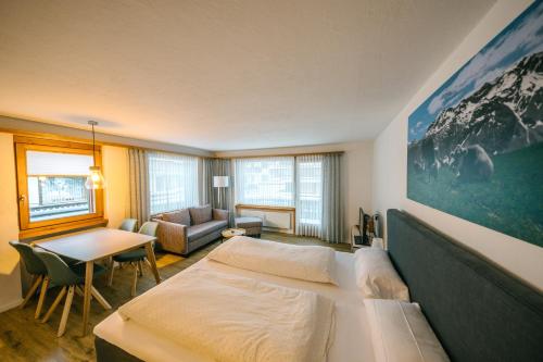 a bedroom with a bed and a couch and a table at Alpina Apartments in Klosters