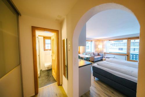 a bedroom with a bed and a living room at Alpina Apartments in Klosters