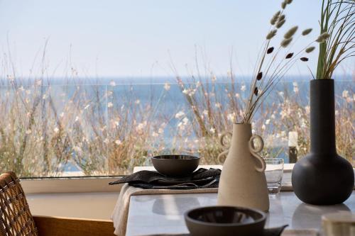 a table with vases on a table with a window at Ios Grand Pool Suites in Mylopotas