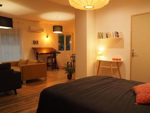 um quarto com uma cama e uma sala de estar com uma mesa em Loft ravissant proche du centre-ville em Nîmes