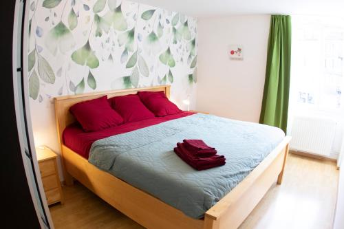 - une chambre avec un lit et des oreillers rouges dans l'établissement Kasa Jura 2 - Centre ville - Proche pistes de ski, à Saint-Claude