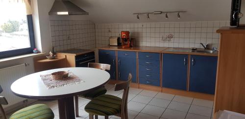 a kitchen with a white table and blue cabinets at Ferienwohnung Karin in Eltmann