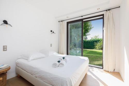 ein Schlafzimmer mit einem weißen Bett und einem großen Fenster in der Unterkunft HSUD0059-Les Ecrins in Mougins