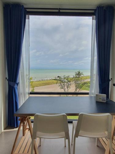 a table and chairs in front of a window with a view at The Beach Resort & Residence - SHA Plus in Pathiu