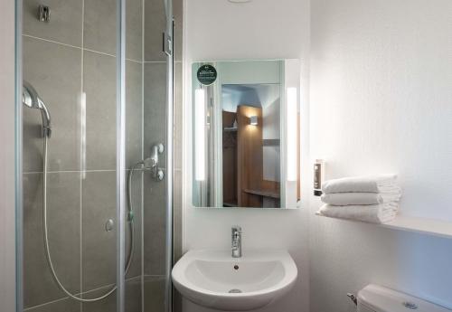 ein Bad mit einem Waschbecken und einer Dusche mit einem Spiegel in der Unterkunft B&B HOTEL Lille Lezennes Stade Pierre Mauroy in Lezennes