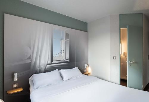 a bedroom with a white bed and a window at B&B HOTEL Lille Lezennes Stade Pierre Mauroy in Lezennes