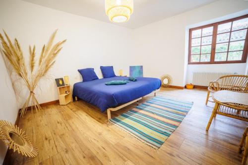 Schlafzimmer mit einem Bett mit blauer Bettwäsche und einem Teppich in der Unterkunft Maison au cœur de Saint-Émilion in Saint-Christophe-des-Bardes