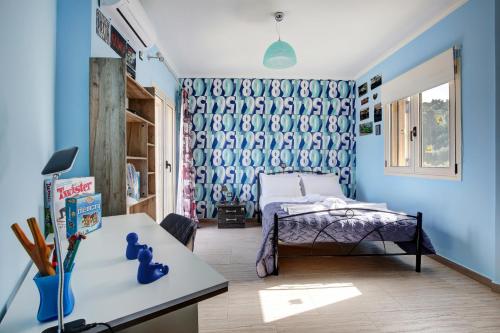 a bedroom with blue walls and a bed and a desk at Cozy family home in Katouna in Katouna