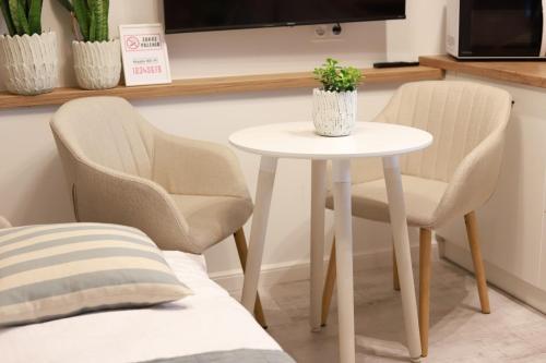 two chairs and a white table with a plant on it at 2 Apartament Miętowy Rumianek in Lwówek