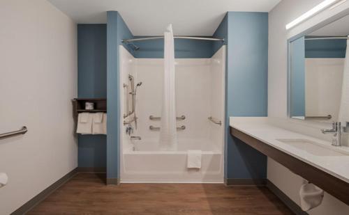 y baño con ducha, bañera y lavamanos. en WoodSpring Suites Moreno Valley, en Moreno Valley