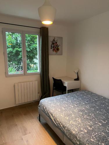 Un dormitorio con una cama y un escritorio y una ventana. en Appartement lumineux près métro, en Saint-Denis