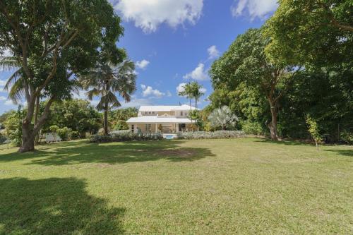 a large yard with a white house with trees at Coral House 3 bedroom home in Saint Peter