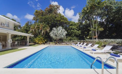 a swimming pool with lounge chairs next to a house at Coral House 3 bedroom home in Saint Peter