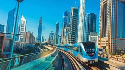 un treno bianco e blu su binari in una città di Stop Over Partition Room in Al Barsha 1 Near Mashreq Metro a Dubai