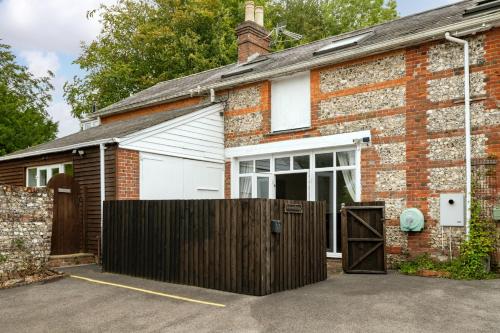 a brick house with a fence in front of it at Primrose - Holiday Cottage with Private Vineyard in Blandford Forum