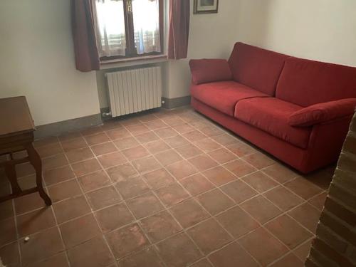 a living room with a red couch and a table at I Casali Della Ghisleria in Ospedalicchio