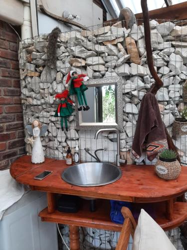 um lavatório de casa de banho com um espelho numa mesa de madeira em Green room em Knysna