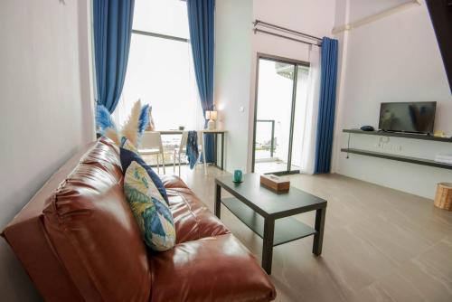 a living room with a brown leather couch and a table at The Beach Resort & Residence - SHA Plus in Pathiu