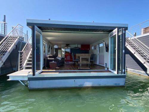 una casa en el agua con un muelle en Hausboot Optimo mit Hund, en Wangerland