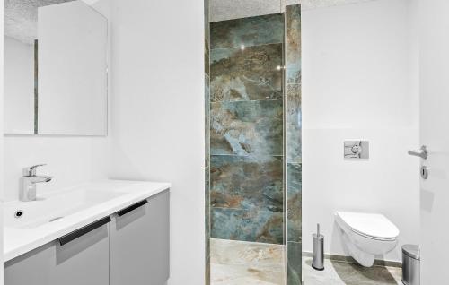 La salle de bains est pourvue de toilettes, d'un lavabo et d'une douche. dans l'établissement Stunning Home In Lgstrup With Kitchen, à Løgstrup