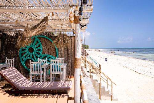 un restaurante en la playa con sillas y el océano en Pili Pili Sunrise en Jambiani