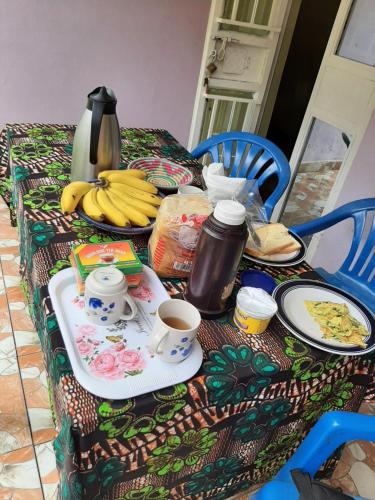 a table with plates of food and bananas on it at Havannah Campsite and Homestay in Fort Portal