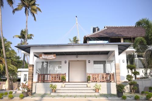 ein weißes Haus mit Palmen davor in der Unterkunft Sandcastle in Kochi