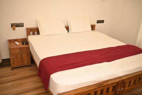 Schlafzimmer mit einem Bett mit weißer und roter Bettwäsche in der Unterkunft Sandcastle in Kochi