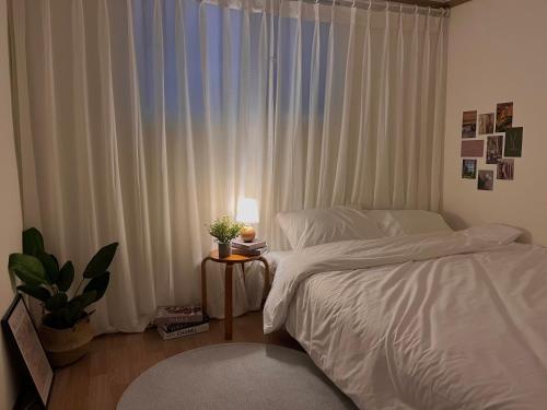 a bedroom with a bed and a table with a plant at Nroo Stay in Seoul
