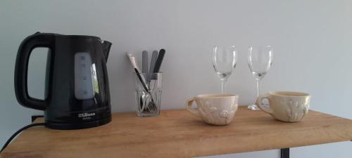 een tafel met een koffiezetapparaat en twee kopjes en wijnglazen bij Cantal Bed & Breakfast in El Durazno