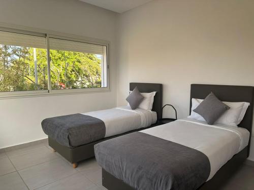 2 camas en una habitación con ventana en Residence Neya Harhoura en Temara