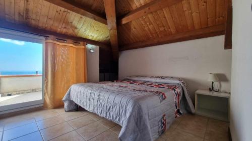 a bedroom with a bed and a large window at Villa immersa nel verde dell Etna in Piedimonte Etneo