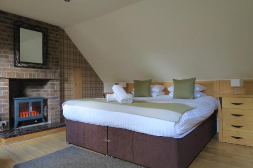 um quarto com uma cama grande e uma lareira em The Inn At Lathones em St. Andrews