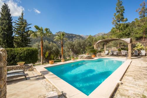a swimming pool in a backyard with trees and mountains at Finca Es Castell in Binibona