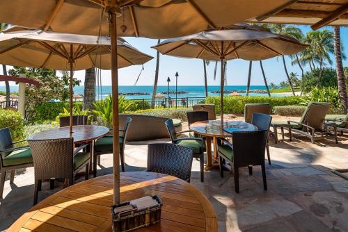 an outdoor patio with tables and chairs and umbrellas at Ko Olina Beach Villas B301 in Kapolei