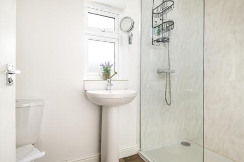uma casa de banho branca com um lavatório e um chuveiro em Dreamwood - Woodland Cottage with Private Hot Tub em Blandford Forum