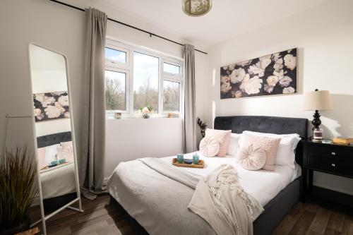 a bedroom with a bed and a mirror and windows at Dreamwood - Woodland Cottage with Private Hot Tub in Blandford Forum