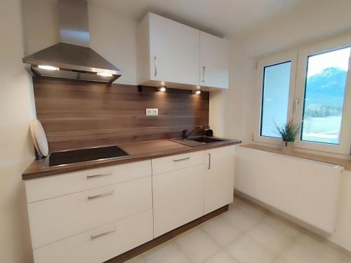 a kitchen with white cabinets and a sink and a window at Carina's Apartment in Obsteig