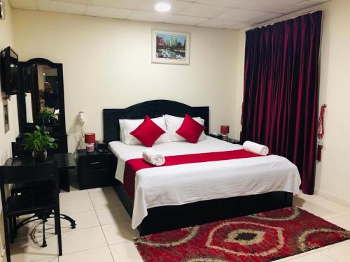 a bedroom with a large bed with red pillows at Miami Hotel Apartment in Sharjah