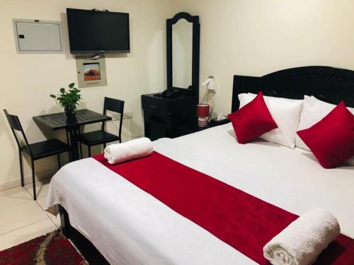 a bedroom with a large bed with red and white pillows at Miami Hotel Apartment in Sharjah