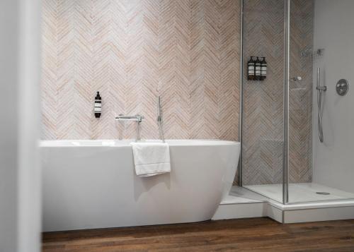 La salle de bains est pourvue d'une baignoire et d'une douche. dans l'établissement Hampshire Hotel – Voncken Valkenburg, à Fauquemont